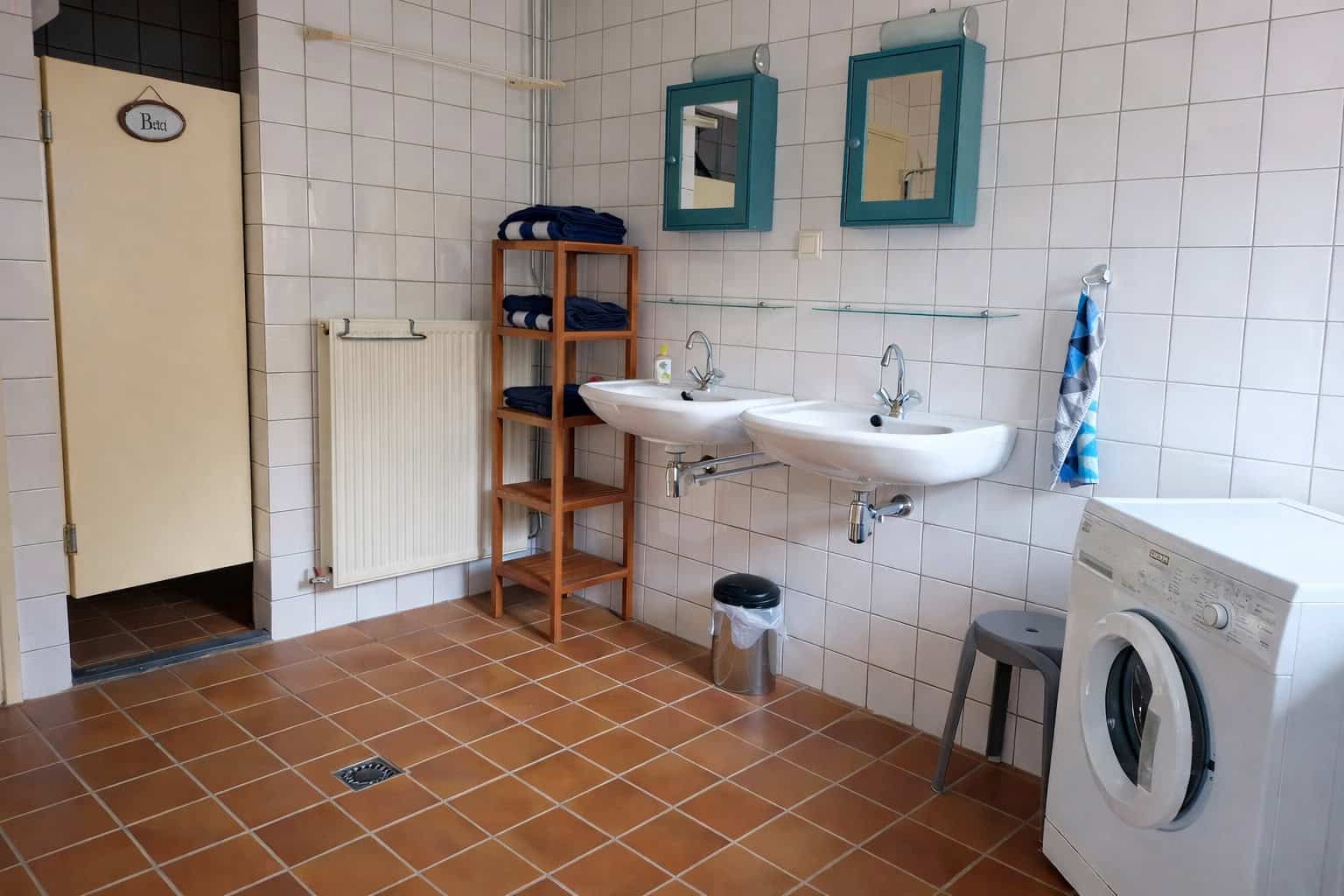 Laundry room with sinks, washing machine, and storage shelves for convenience.