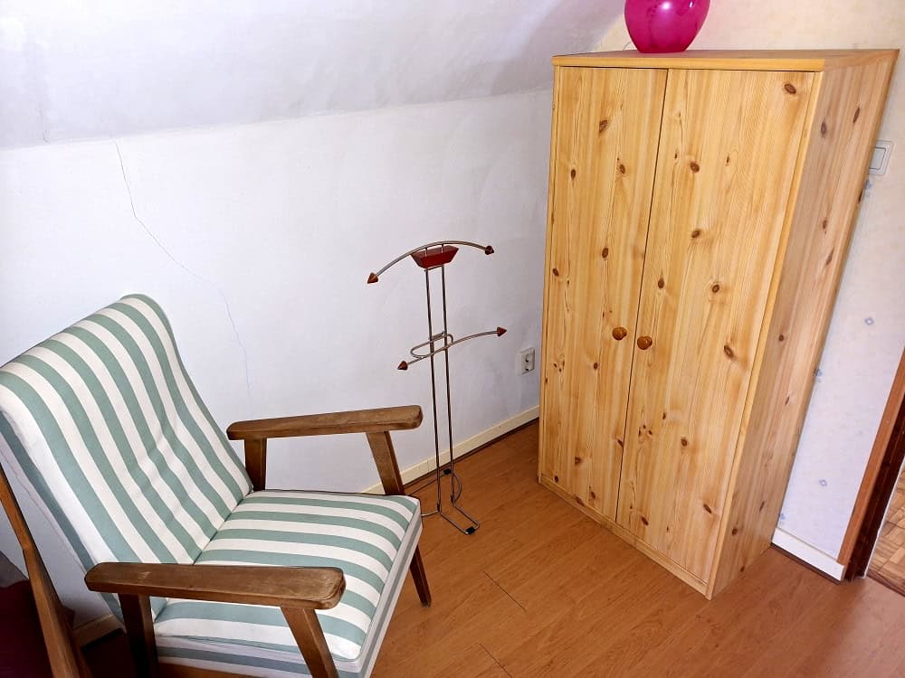 Wooden wardrobe and striped armchair in a cozy room corner.