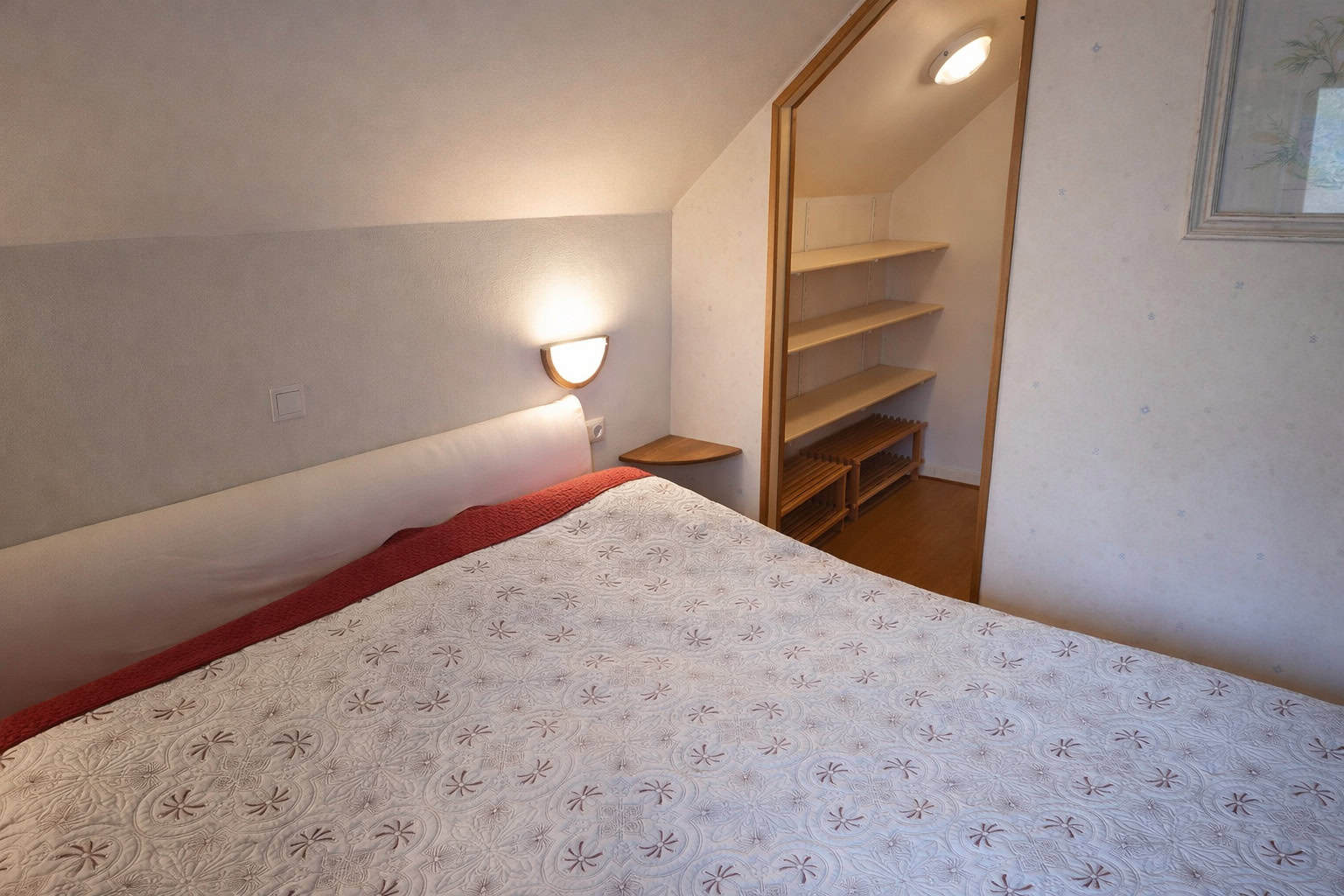 Cozy bedroom featuring a large bed, soft lighting, and built-in shelves for storage. Perfect for rel.