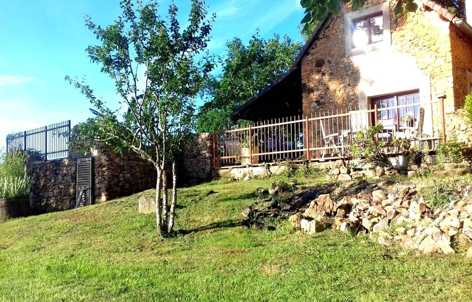 Beautiful stone house with a lush garden and mature trees in a peaceful rural setting.