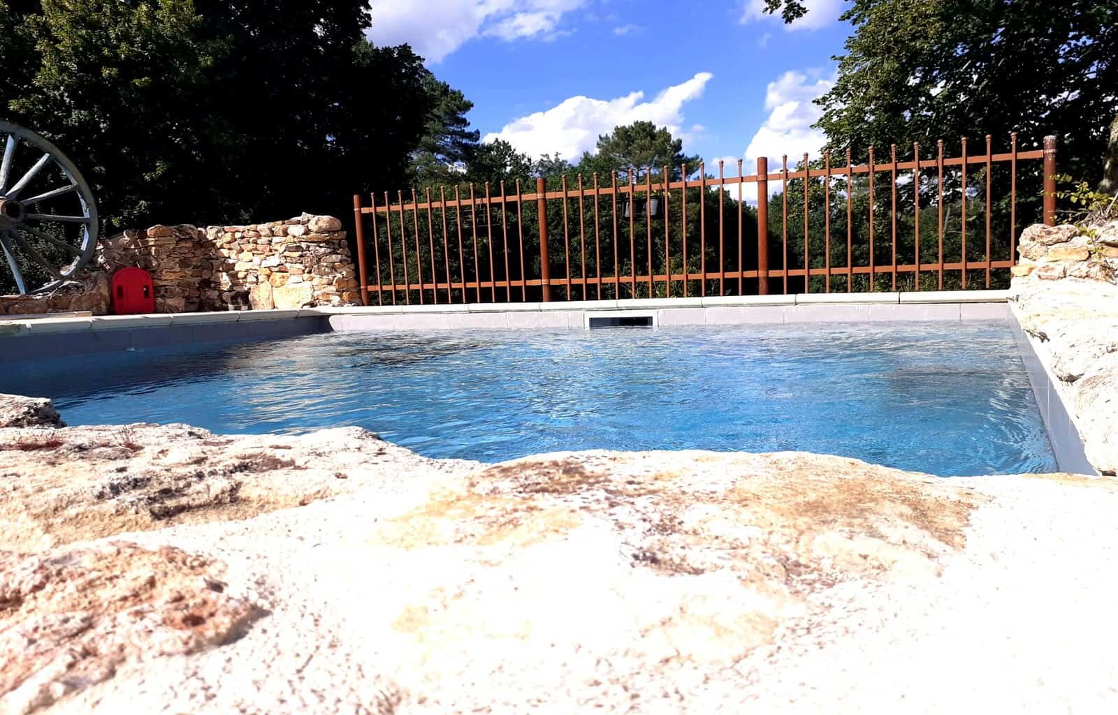 Pool with stone edge and scenic landscape in the background.
