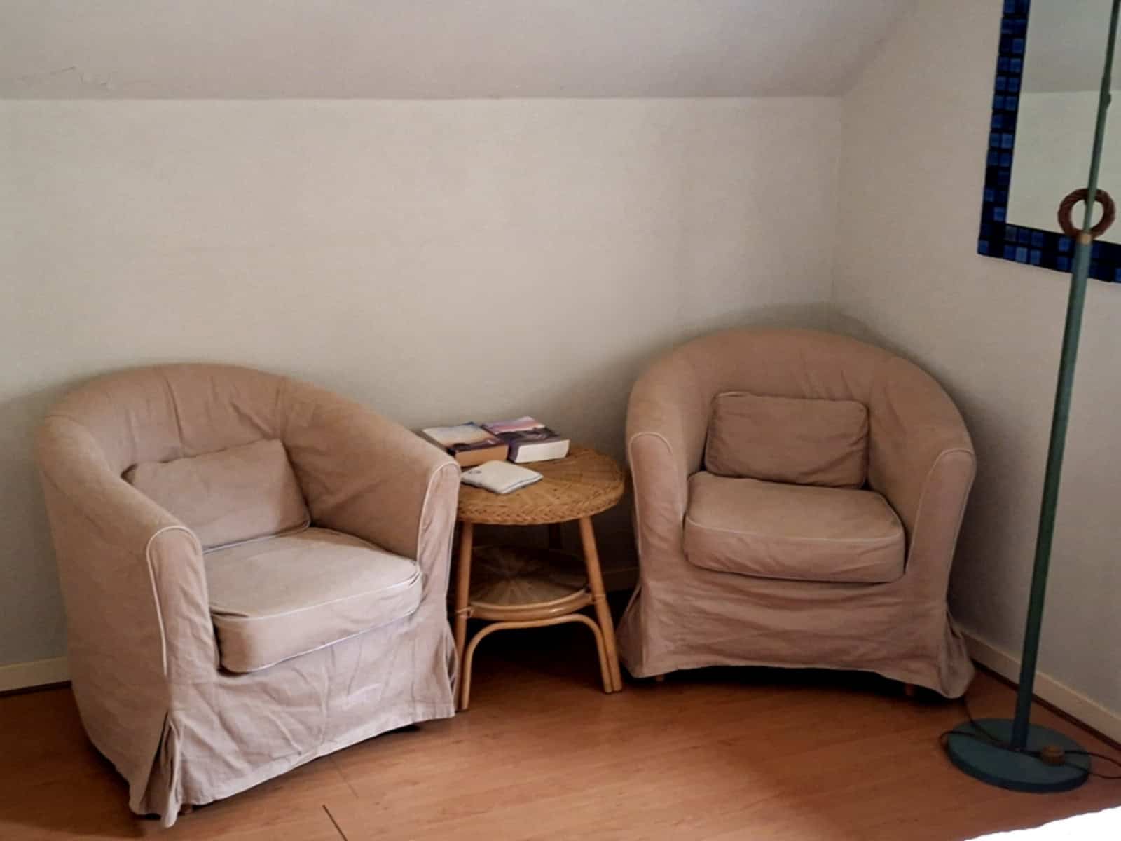 Comfortable beige armchairs with a wooden side table in a cozy living space.